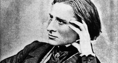 Franz Liszt leaning graciously on a piano